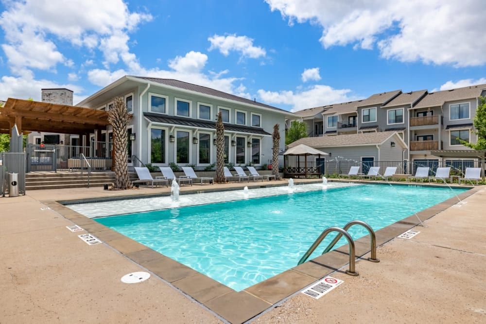 A large swimming pool in front of the clubhouse building at Marquis SoCo in South Austin, TX.