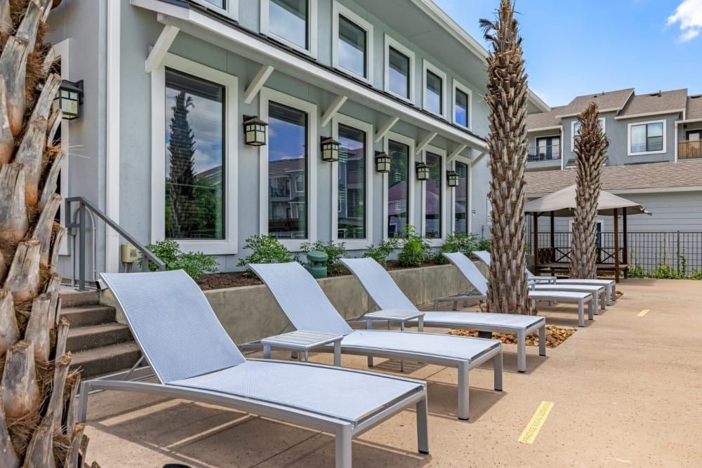 A row of lounge chairs are lined up next to the swimming pool at Marquis SoCo in South Austin, TX.