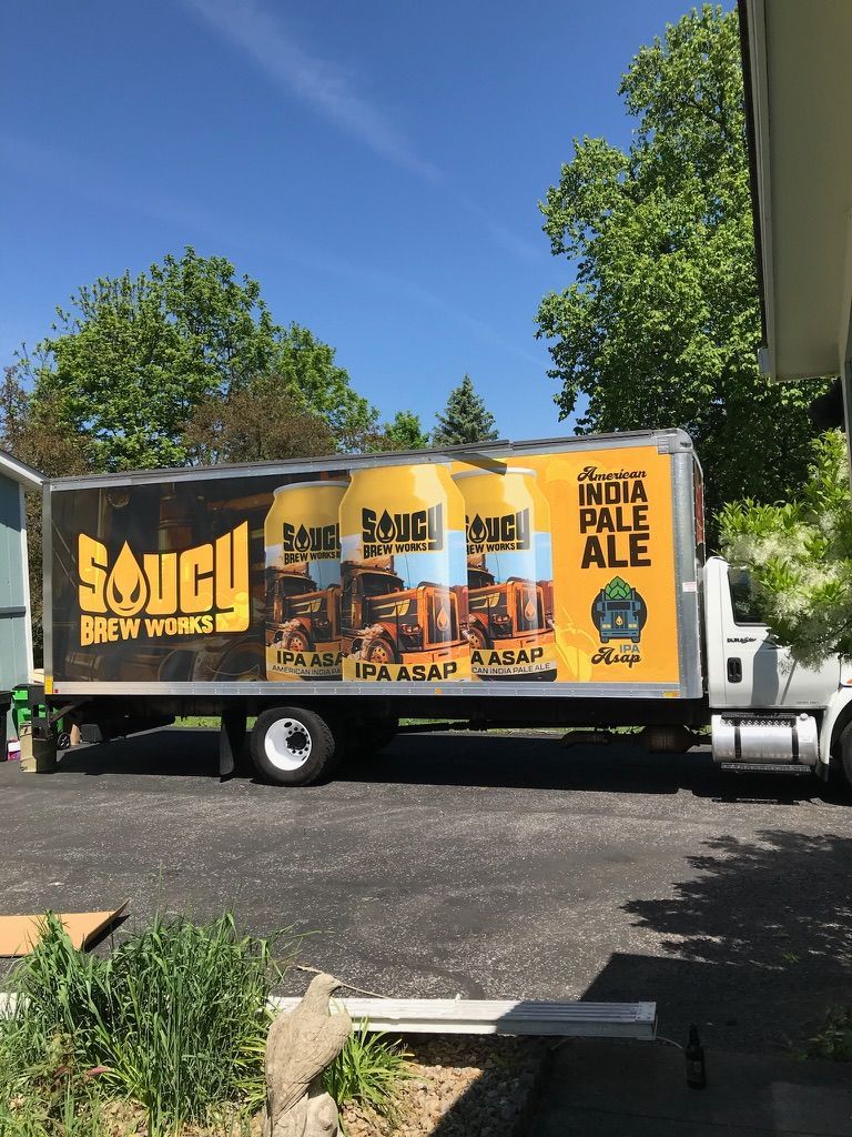 Beer delivery truck with colorful Maui Brewing Company Pale Ale ad parked on a sunny street