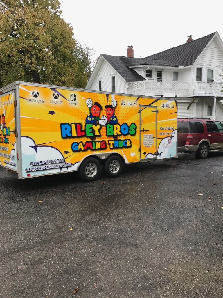 Bright yellow Riley Bros Carnival Foods trailer parked beside a white house and red SUV