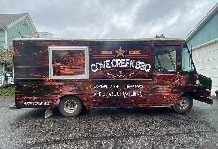 Cove Creek BBQ food truck with red wood-grain wrap parked outdoors