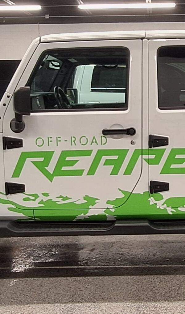 White off-road vehicle with green “REAPER” lettering parked indoors on a wet floor