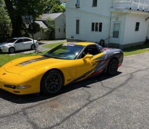 Yellow sports car with black and red graphics parked on a residential street