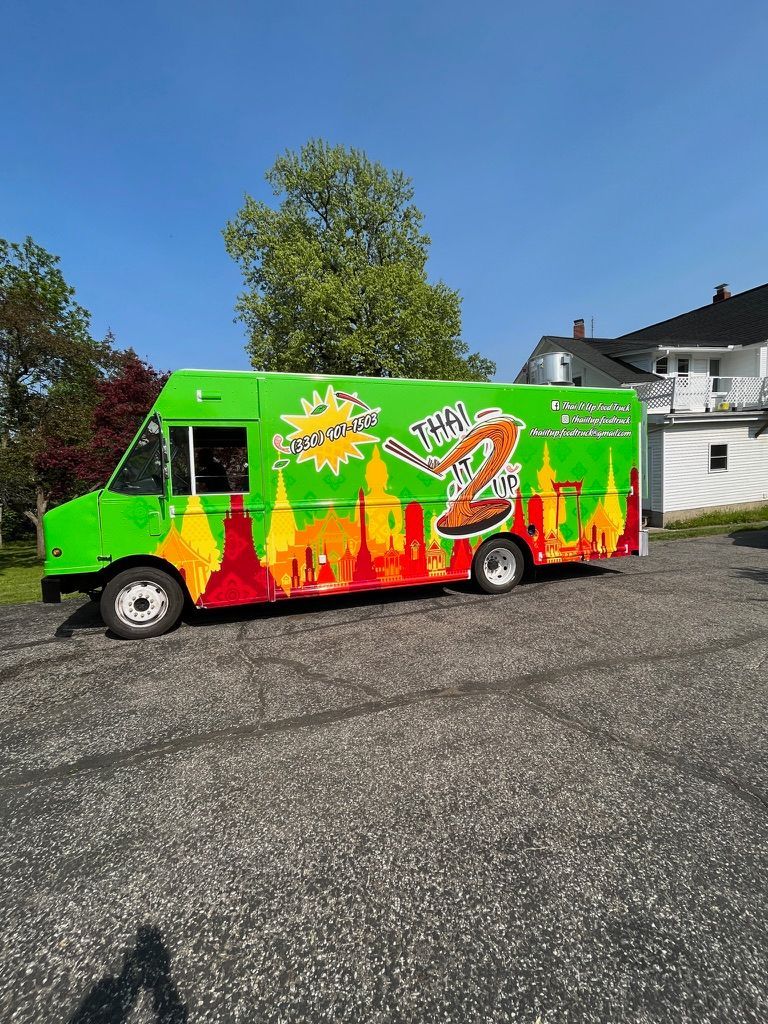 Bright green ice cream truck with colorful graphics parked outdoors under a blue sky.