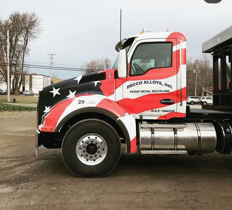 Custom semi-truck cab painted red, white, and black with stars, parked outdoors.