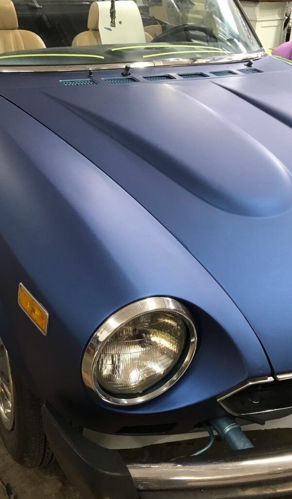 Blue classic car front hood with round headlight in a garage or showroom