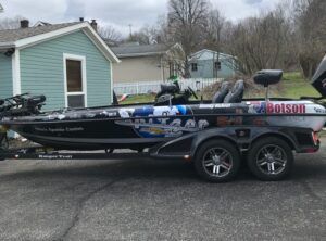 Fishing boat on a trailer parked in a driveway beside a house