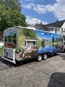 Colorful mobile tiny house trailer with mural art parked on a sunny street