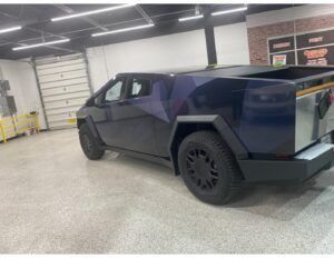 Dark purple Tesla Cybertruck parked inside a garage or showroom