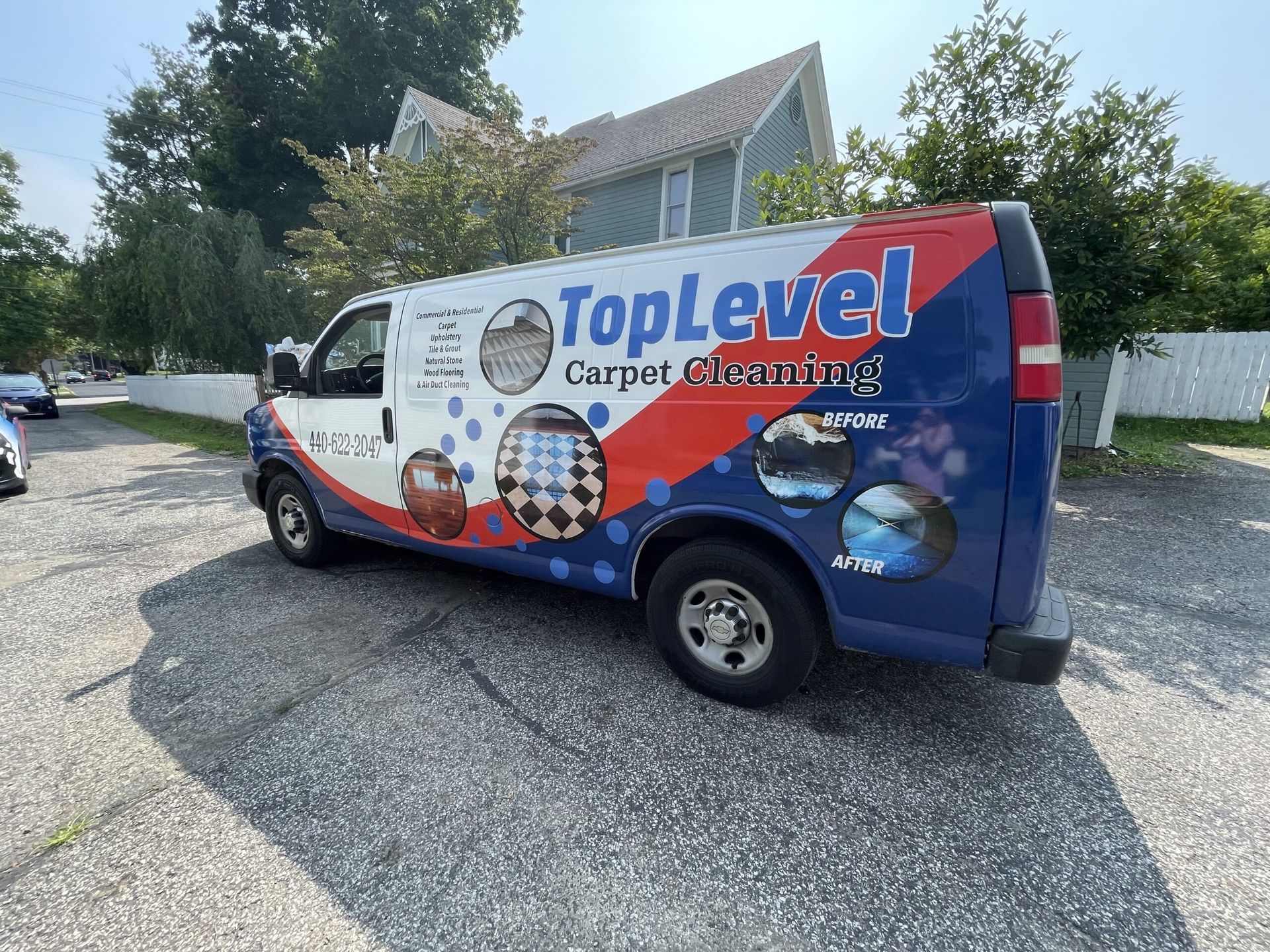 TopLevel Carpet Cleaning van parked on gravel beside a road, with blue and red company branding.