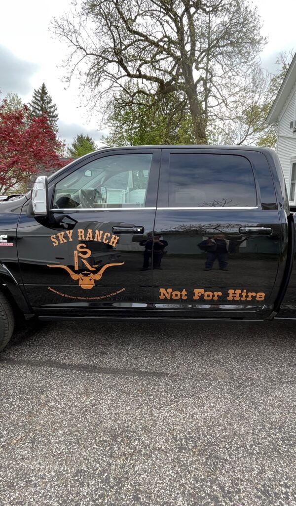 Black pickup truck with “Rat Race” and “Not For Hire” decals parked outdoors