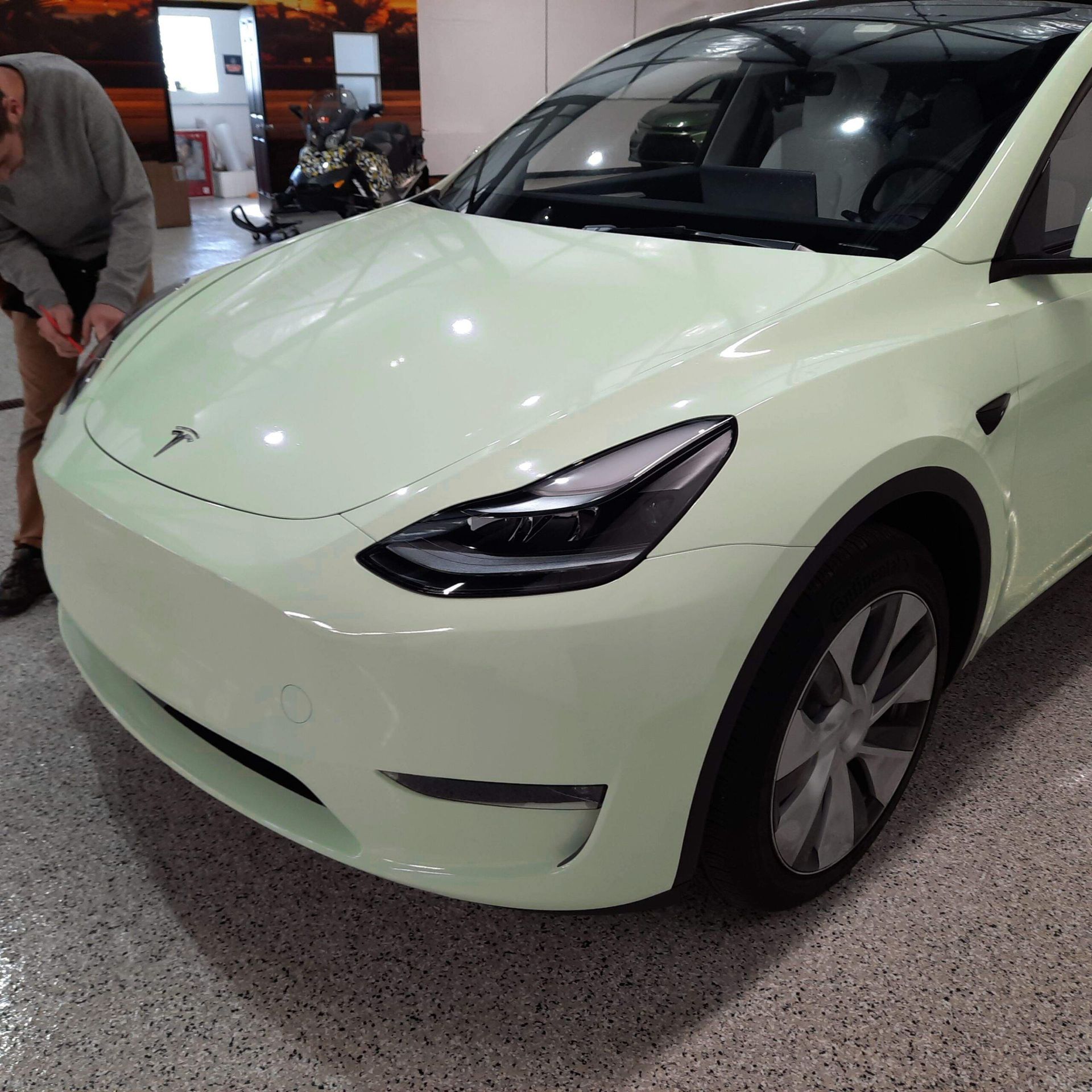 Light mint-green Tesla Model Y parked indoors, front-left view.