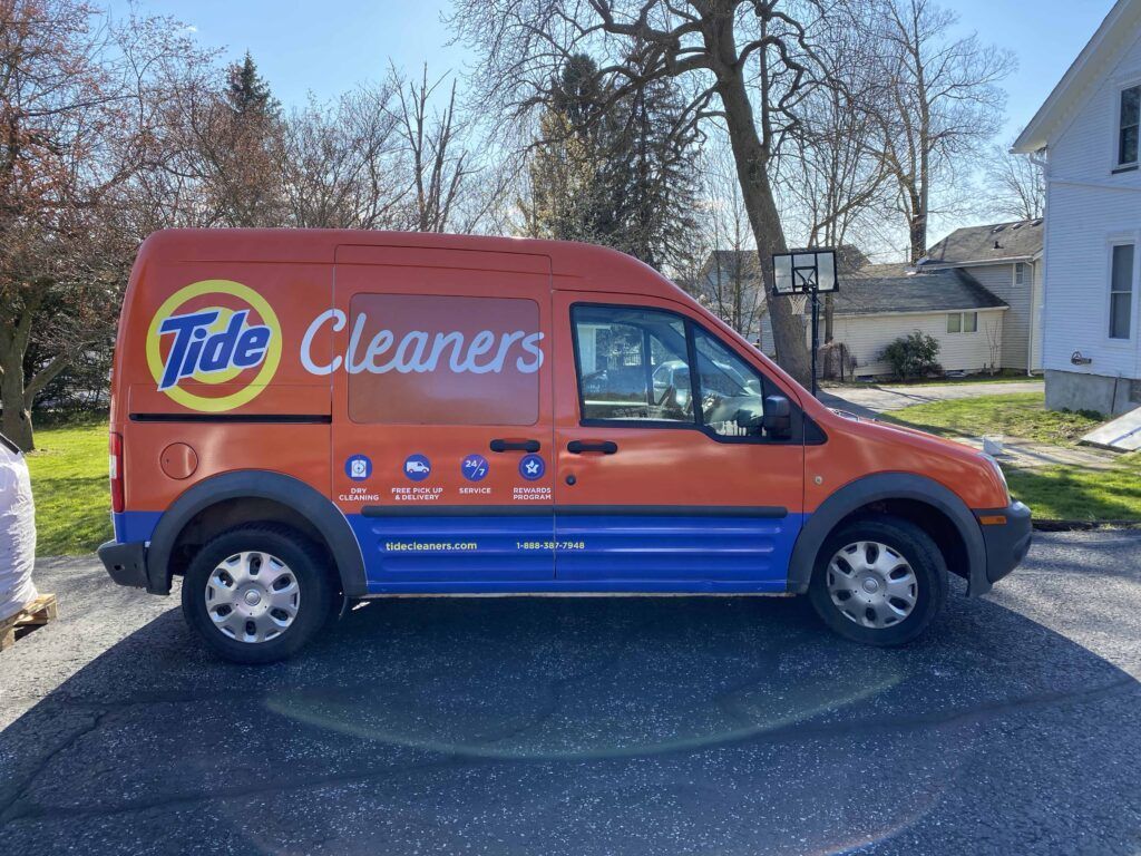 Orange and blue Tide Cleaners van parked on a residential street