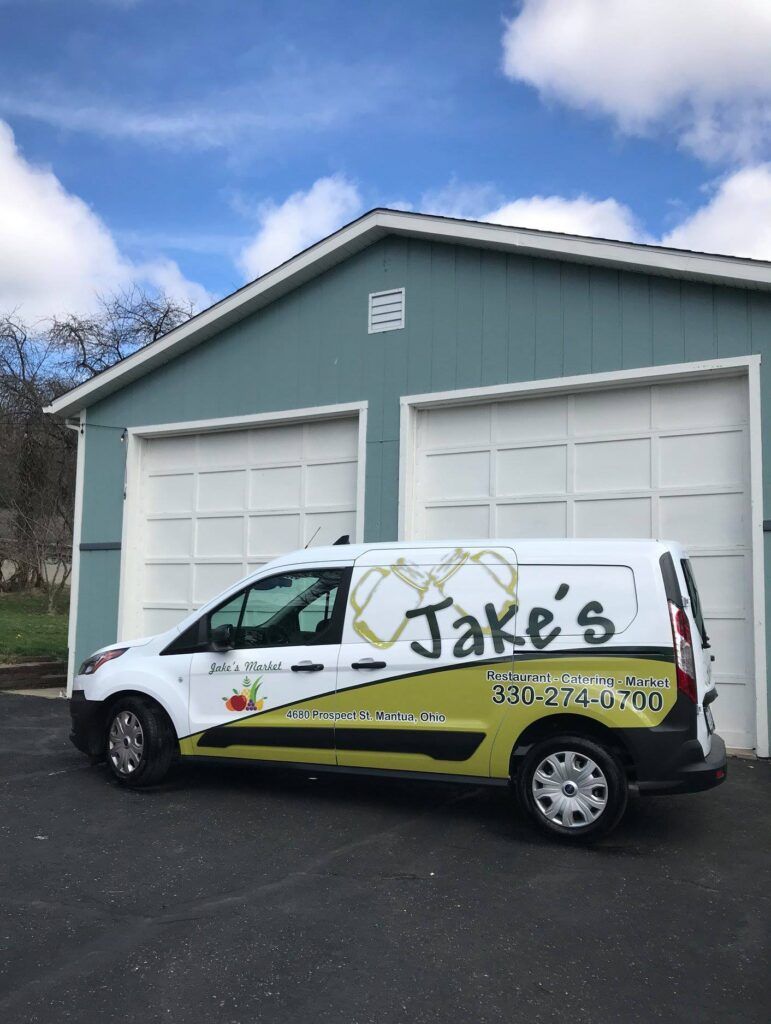 White Jake’s delivery van parked in front of a gray garage.