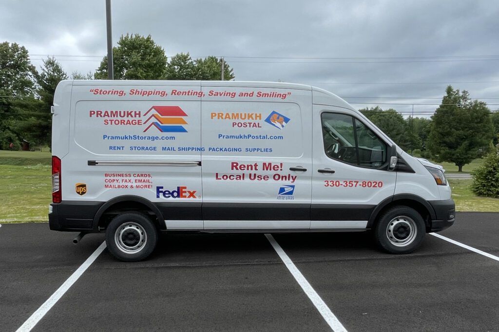 White delivery van with company logos parked in an empty lot under cloudy skies