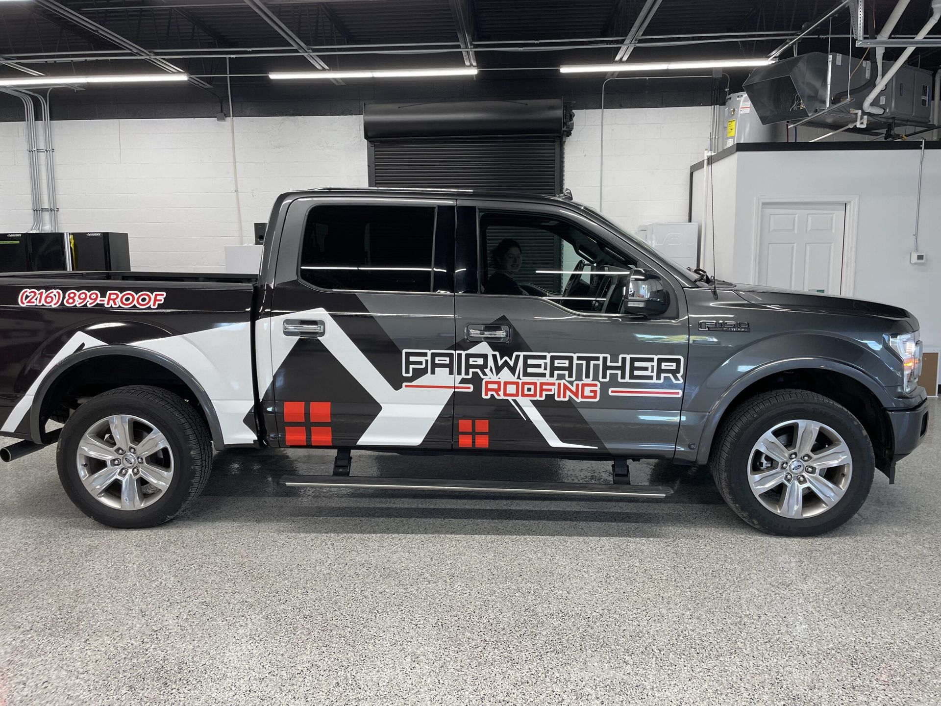 Black pickup truck with “Firefighter Hooks” graphics parked indoors in a garage.
