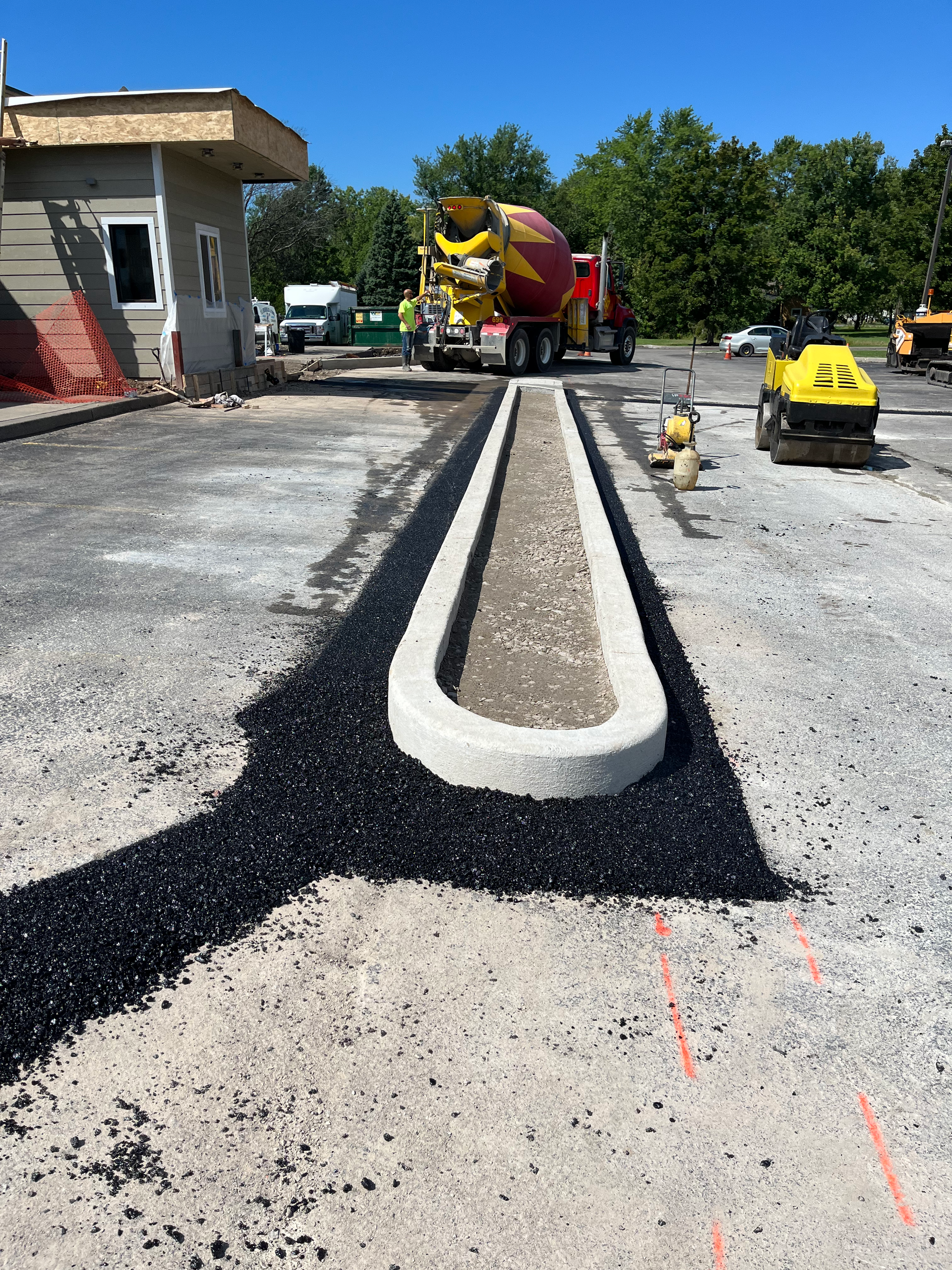 Wide-angle view of a commercial paving project by Universal Paving & Concrete in Rochester, NY, showing a newly paved business driveway and parking lot.