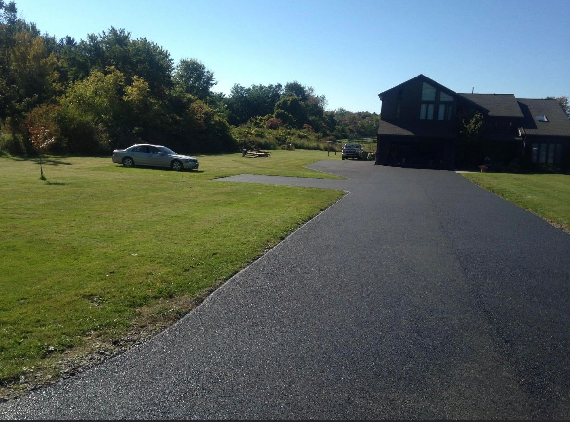 Before and after image of an asphalt driveway installation in Rochester, NY by Universal Paving & Concrete, showing dramatic transformation.