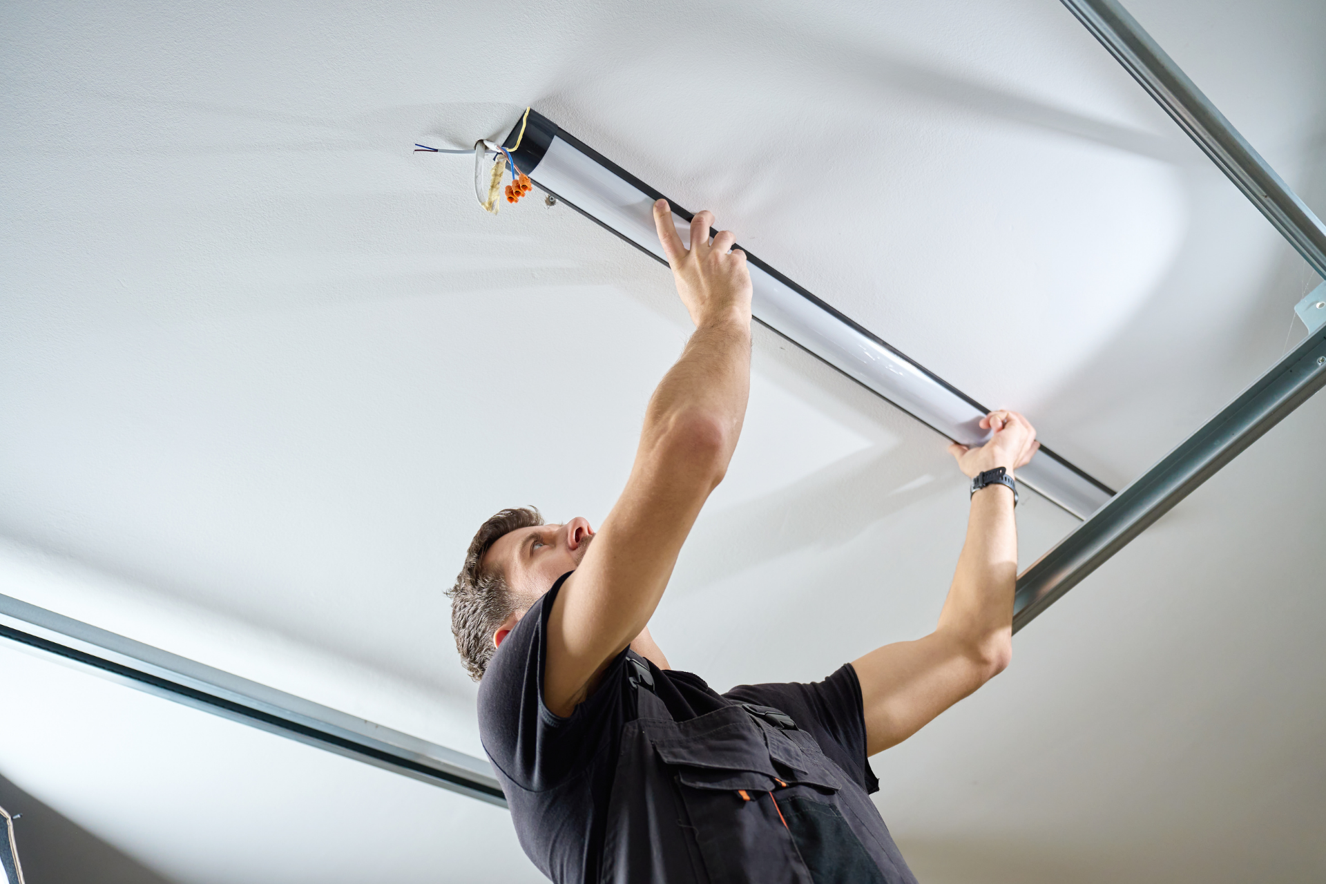 Worker installing a garage door opener on a ceiling track