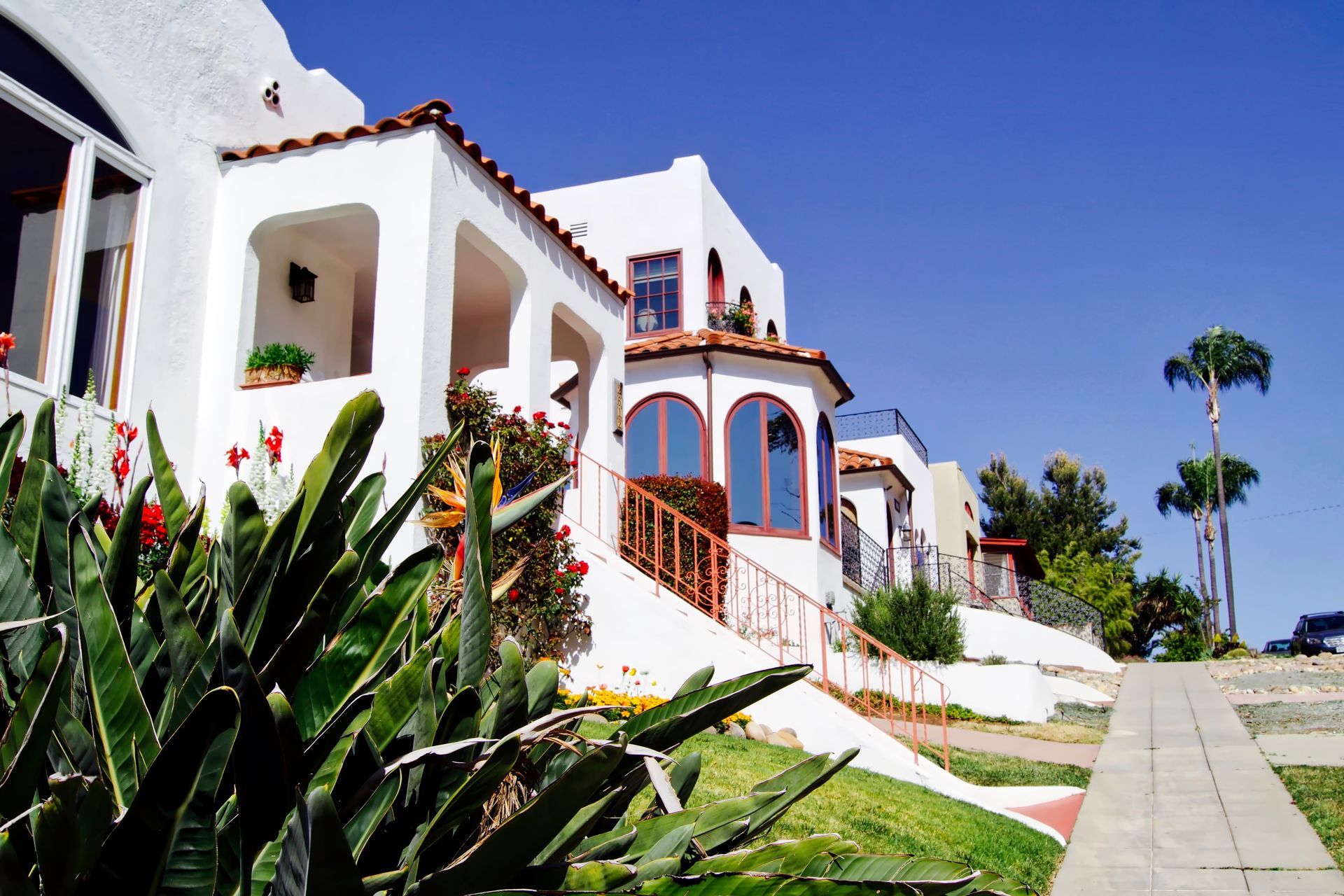 A white house with a red tile roof sits on top of a lush green hillside