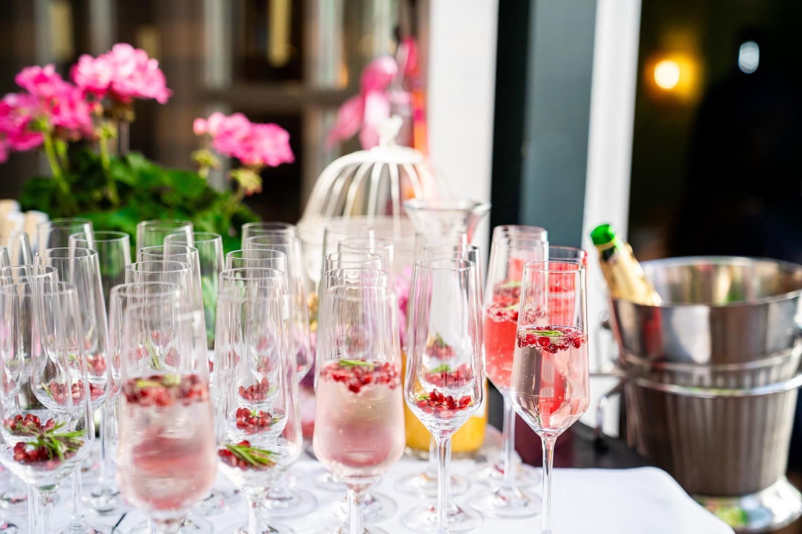 Gläser mit rosafarbenen Cocktails und Beeren auf einem dekorierten Tisch bei einer Party