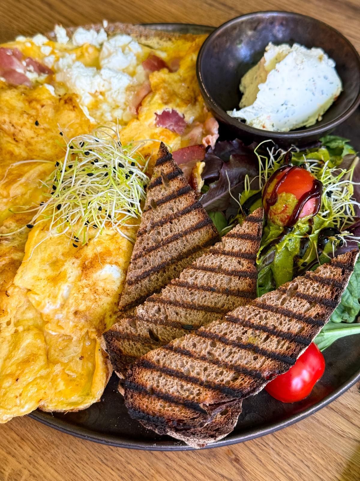 Gegrilltes Steak mit Omelett, Kartoffeln, Salat und Reis auf einem schwarzen Teller