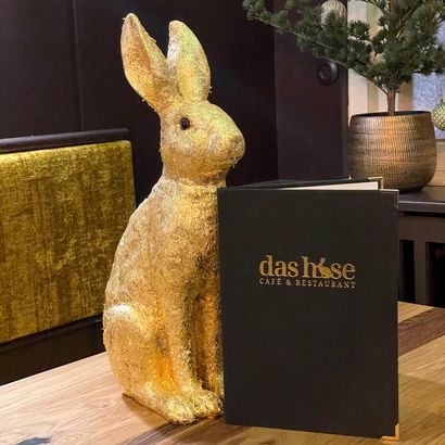 Goldene Hasenskulptur neben schwarzem Das Haus-Schild in einer Lobbyauslage