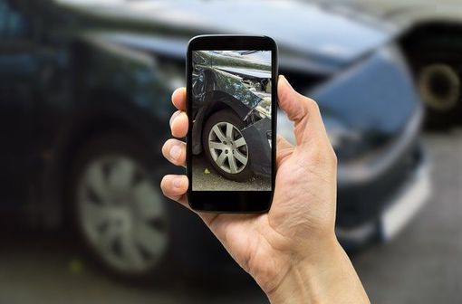 a person is holding a cell phone with a picture of a car on the screen .