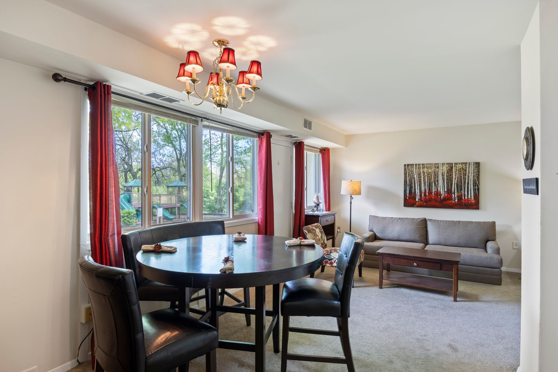 A living room with a dining table and chairs and a chandelier.