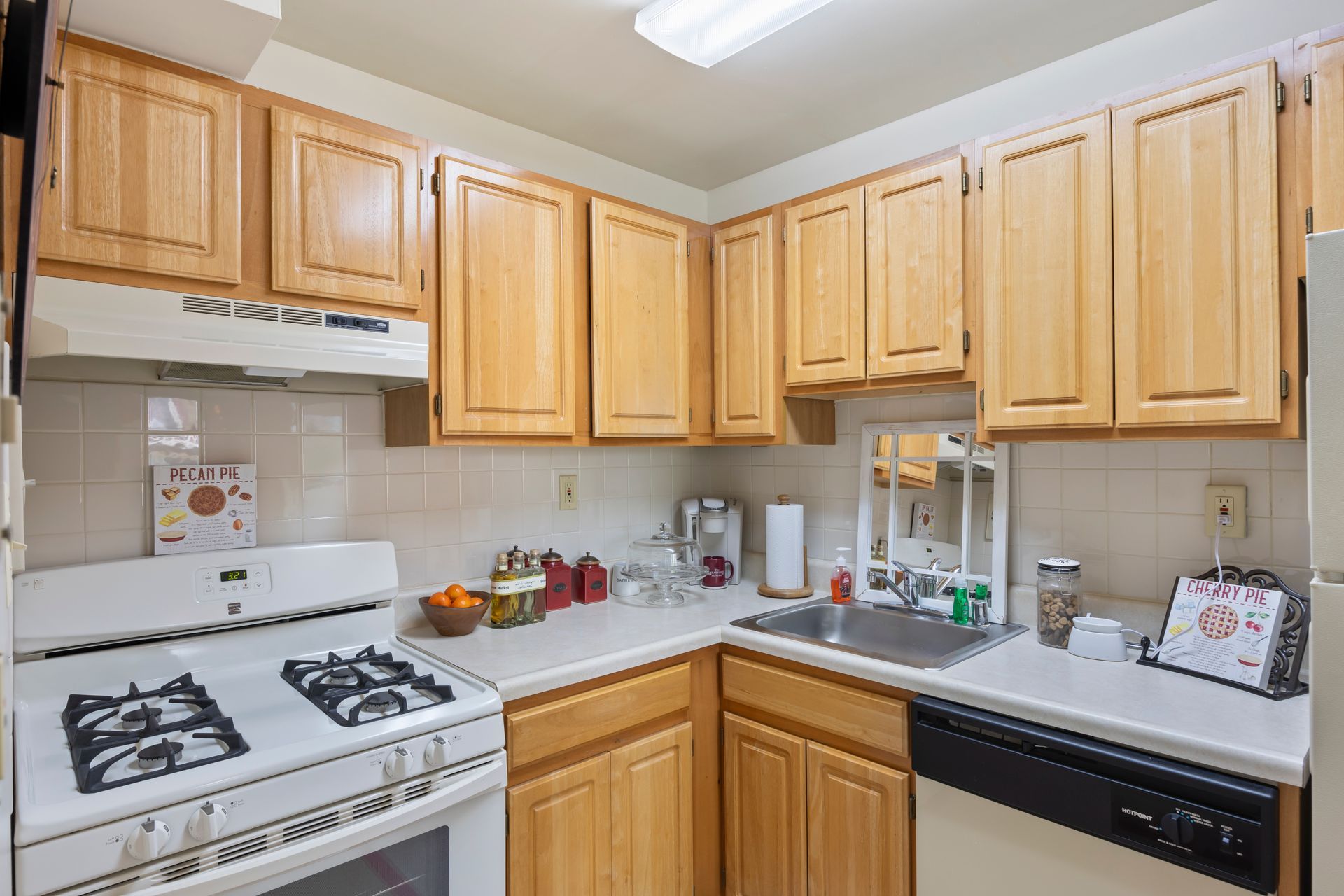 A kitchen with wooden cabinets , a stove , a sink , and a dishwasher.