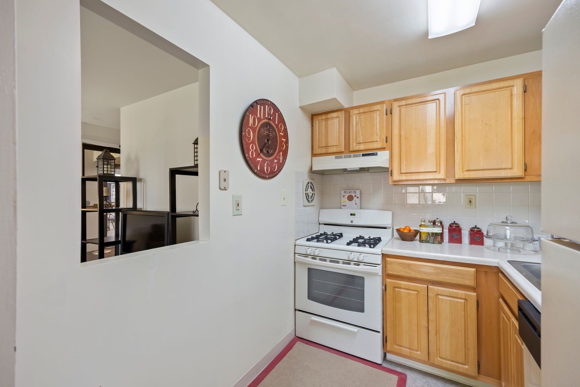 A kitchen with wooden cabinets and a clock on the wall
