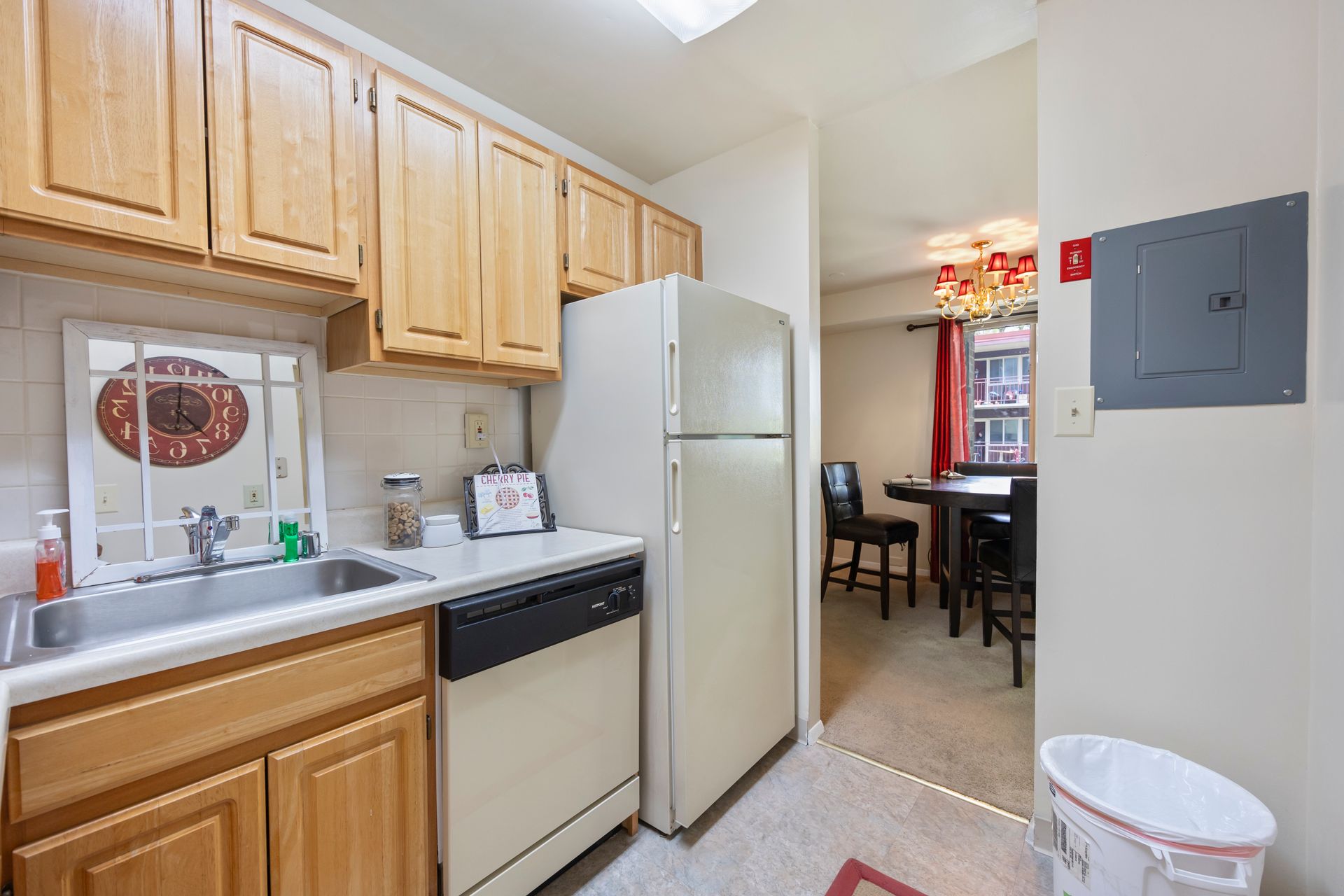 A kitchen with a refrigerator , dishwasher , sink and trash can.