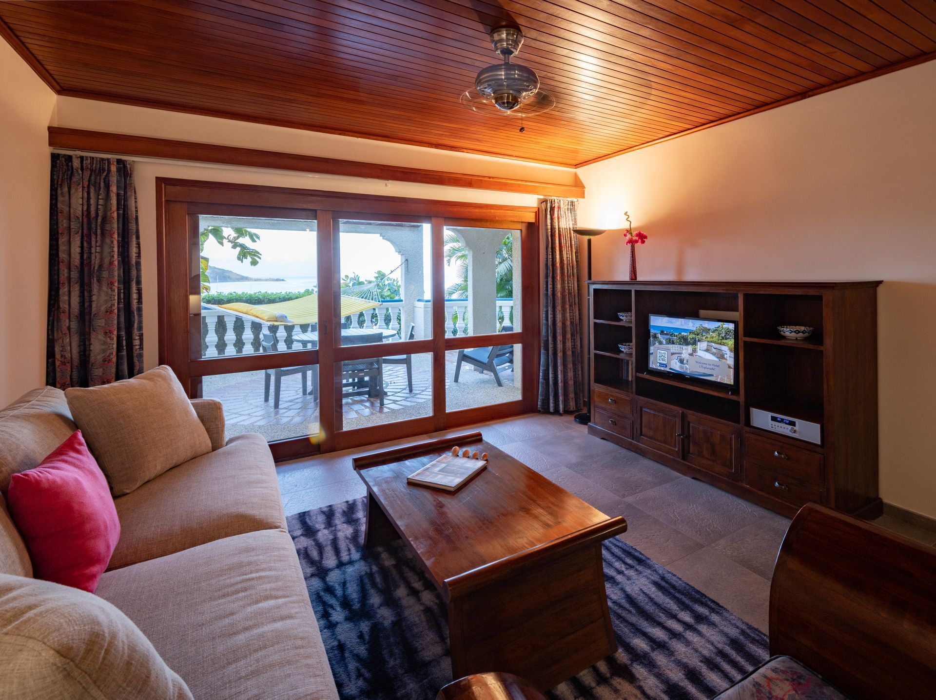 Living room with tan couch, wooden furniture, and sliding glass doors to a patio.
