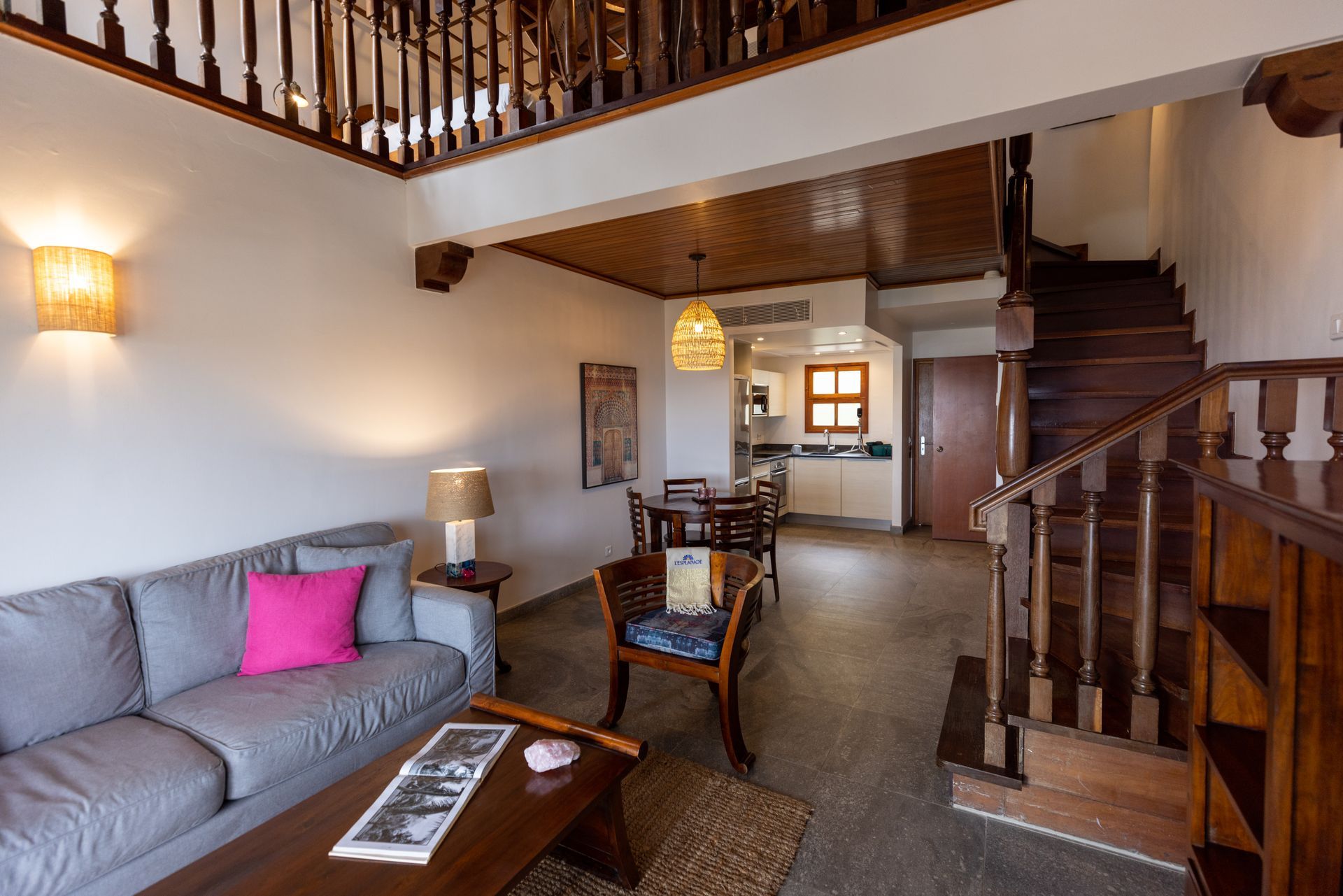 Cozy living area with a gray couch, wooden stairs, and a dining area, featuring a loft.