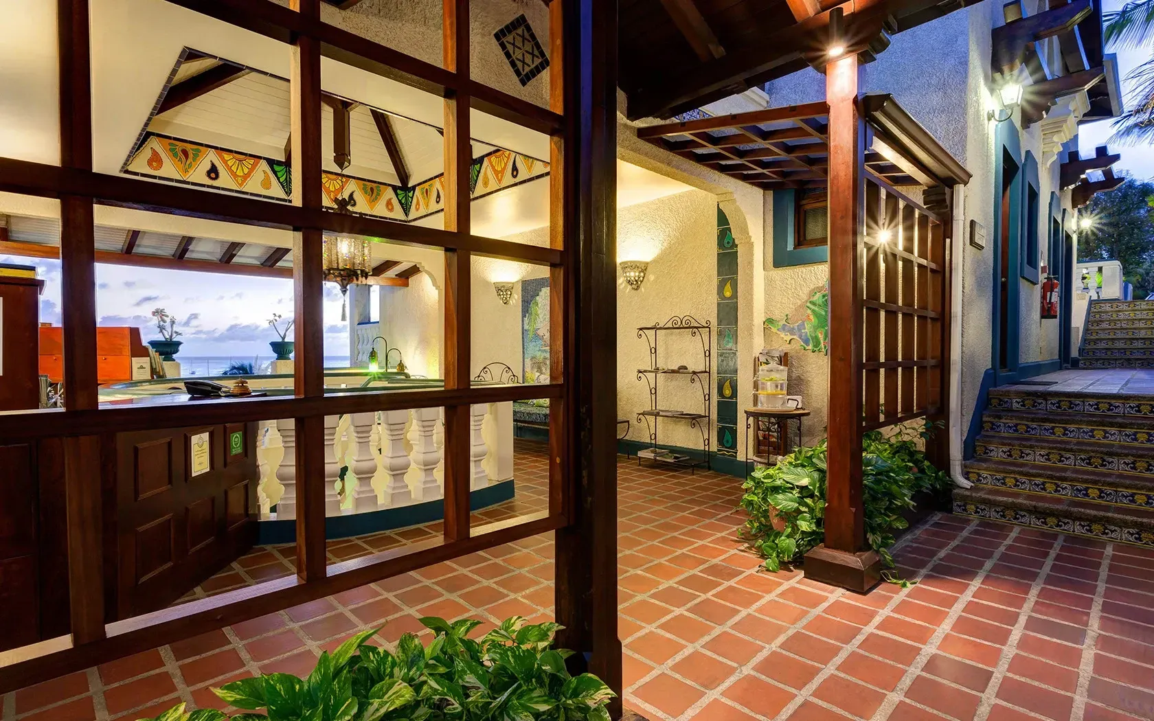 Courtyard with tiled floors, wooden beams, plants, and open doorway to a reception area.