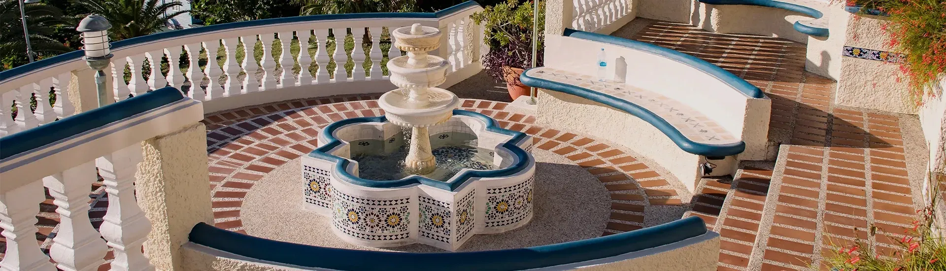 Outdoor patio with a white fountain, benches, and brick paving.