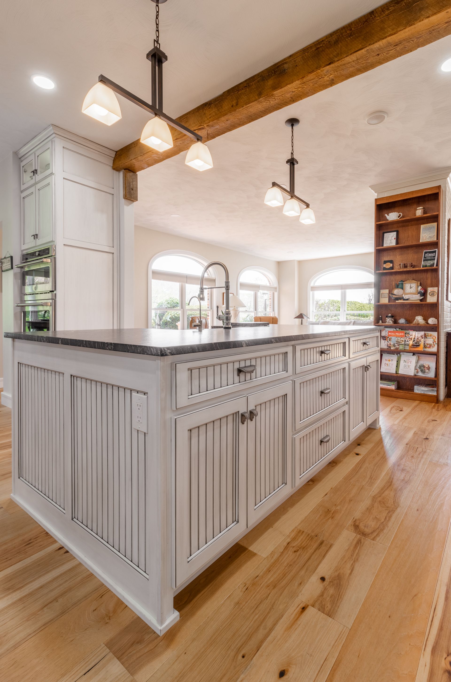 Kitchen island with white cabinets, dark countertop, and light wood floors. Overhead lighting.