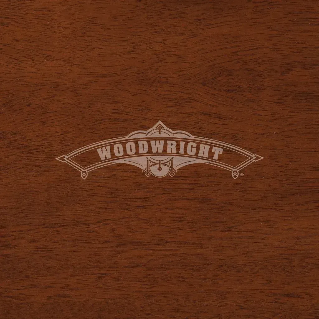 Woodwright logo on a dark wood surface. The logo is a light color.