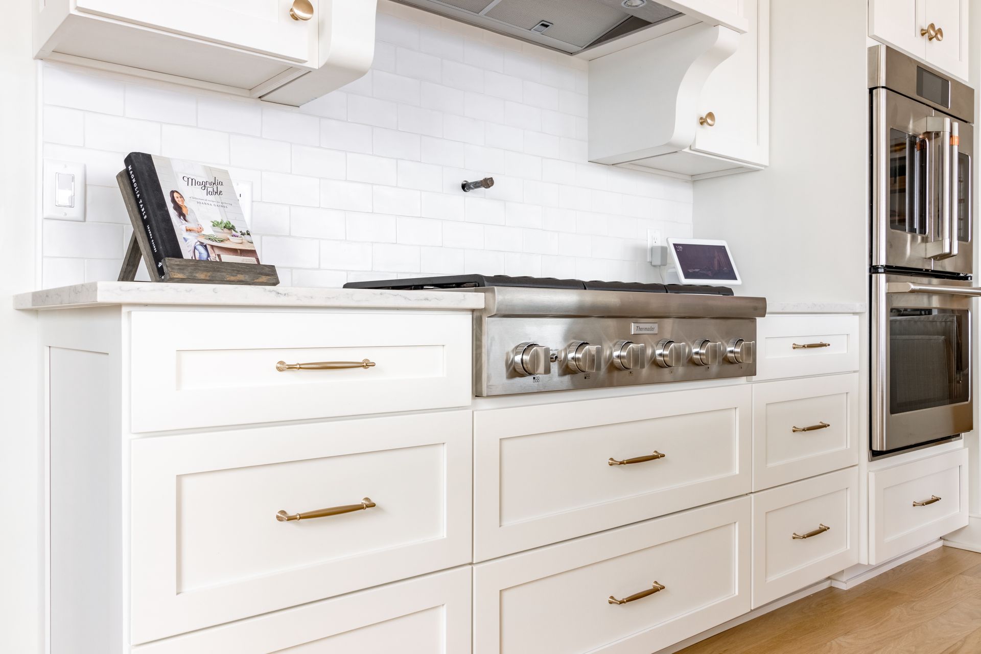 White kitchen with gas range, oven, and cabinets, featuring gold hardware.