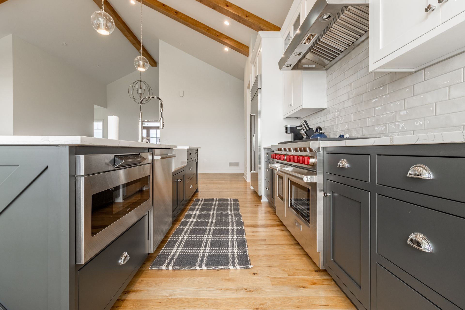 Modern kitchen with grey cabinets, stainless steel appliances, and wood flooring.
