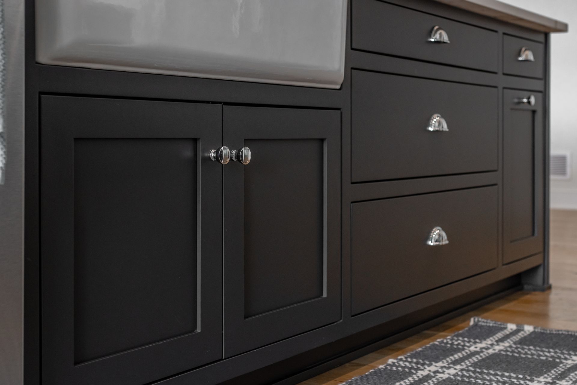 Black kitchen island cabinets with silver hardware, white sink.