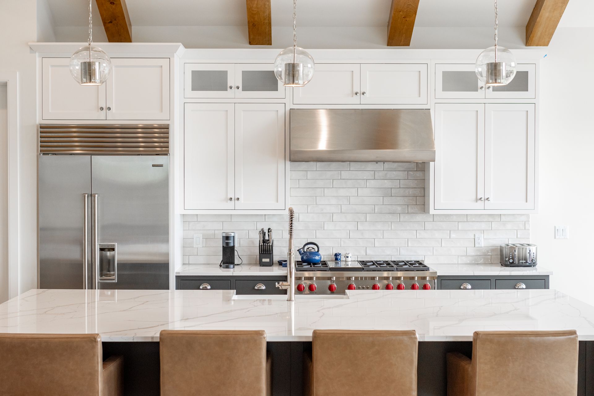 Modern kitchen with white cabinets, stainless steel appliances, and a marble countertop.