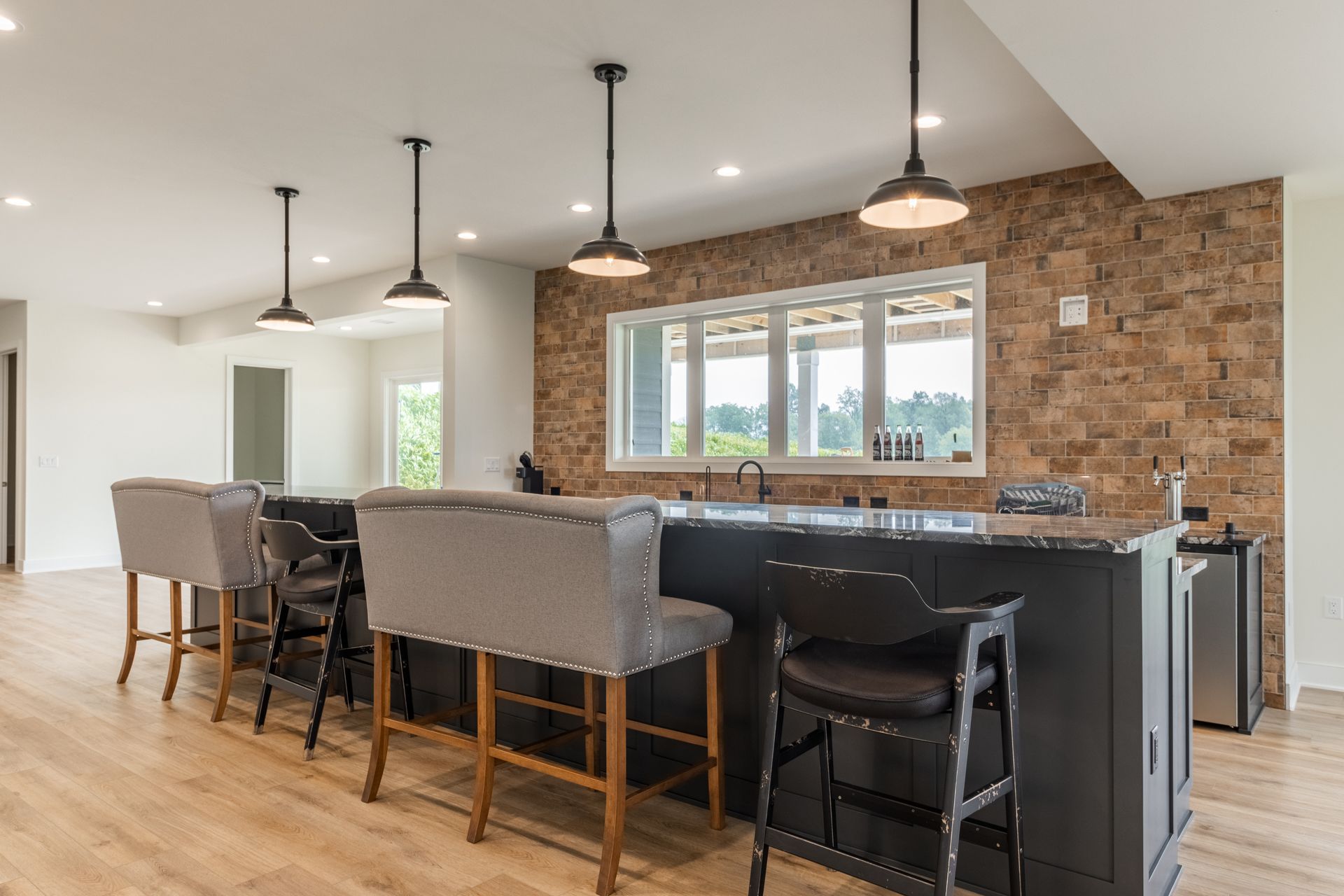 Kitchen with dark island, pendant lights, bar stools, and stone accent wall.
