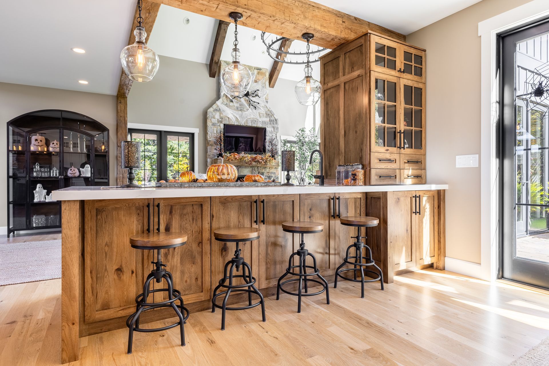 Rustic wooden bar with stone fireplace in background. Bar stools and hanging lights.