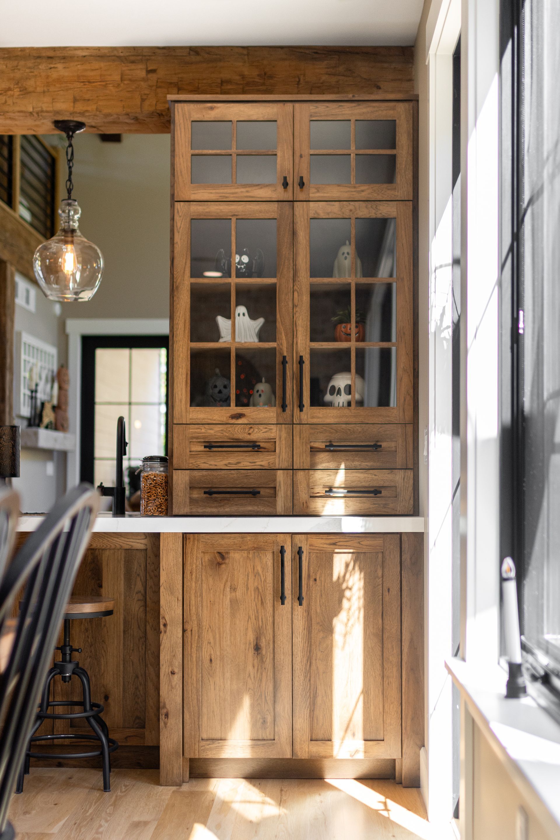 Wooden cabinet with glass-fronted doors, filled with spooky decorations, in a well-lit interior.
