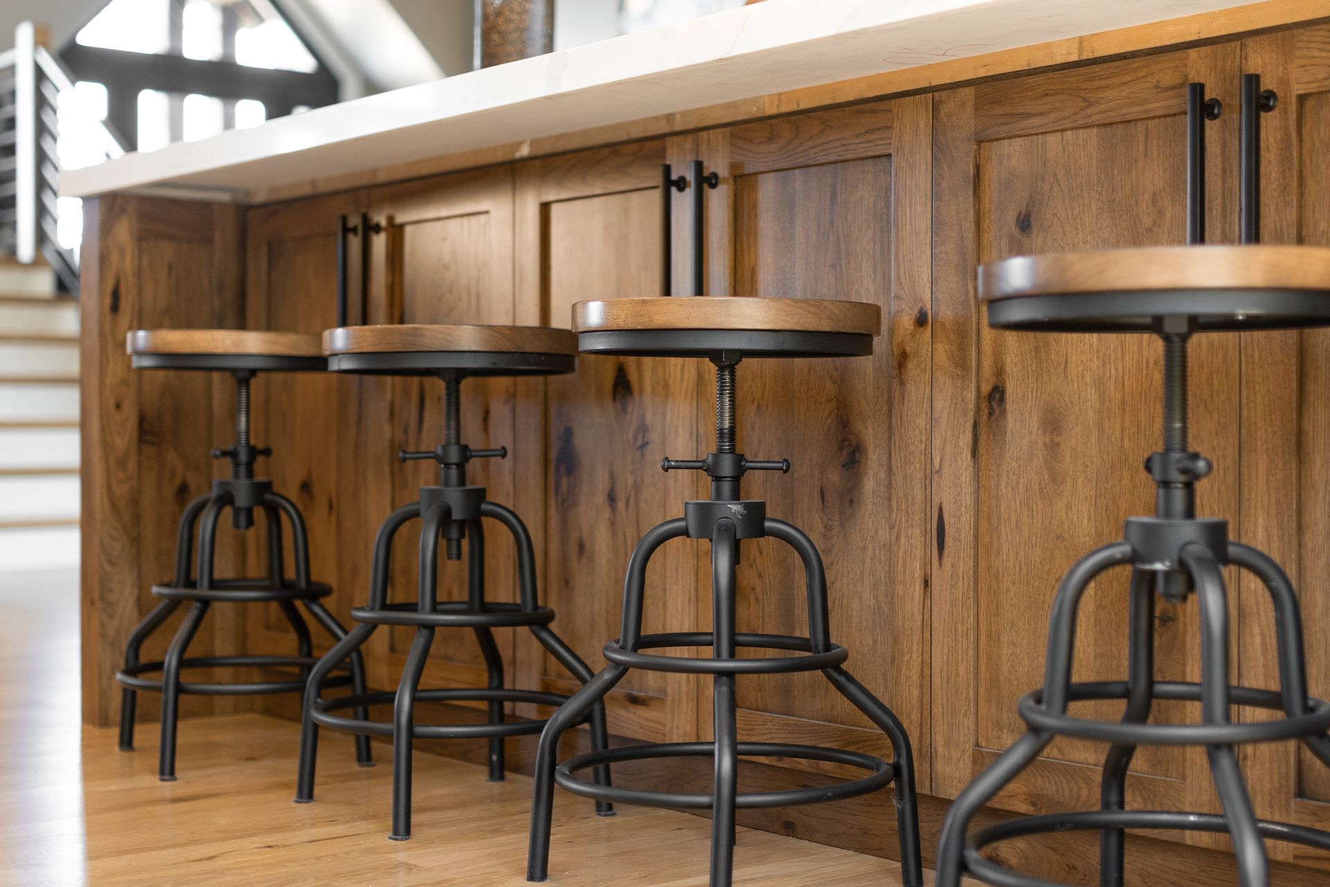 Four industrial-style bar stools with wooden seats in front of a wooden kitchen island.