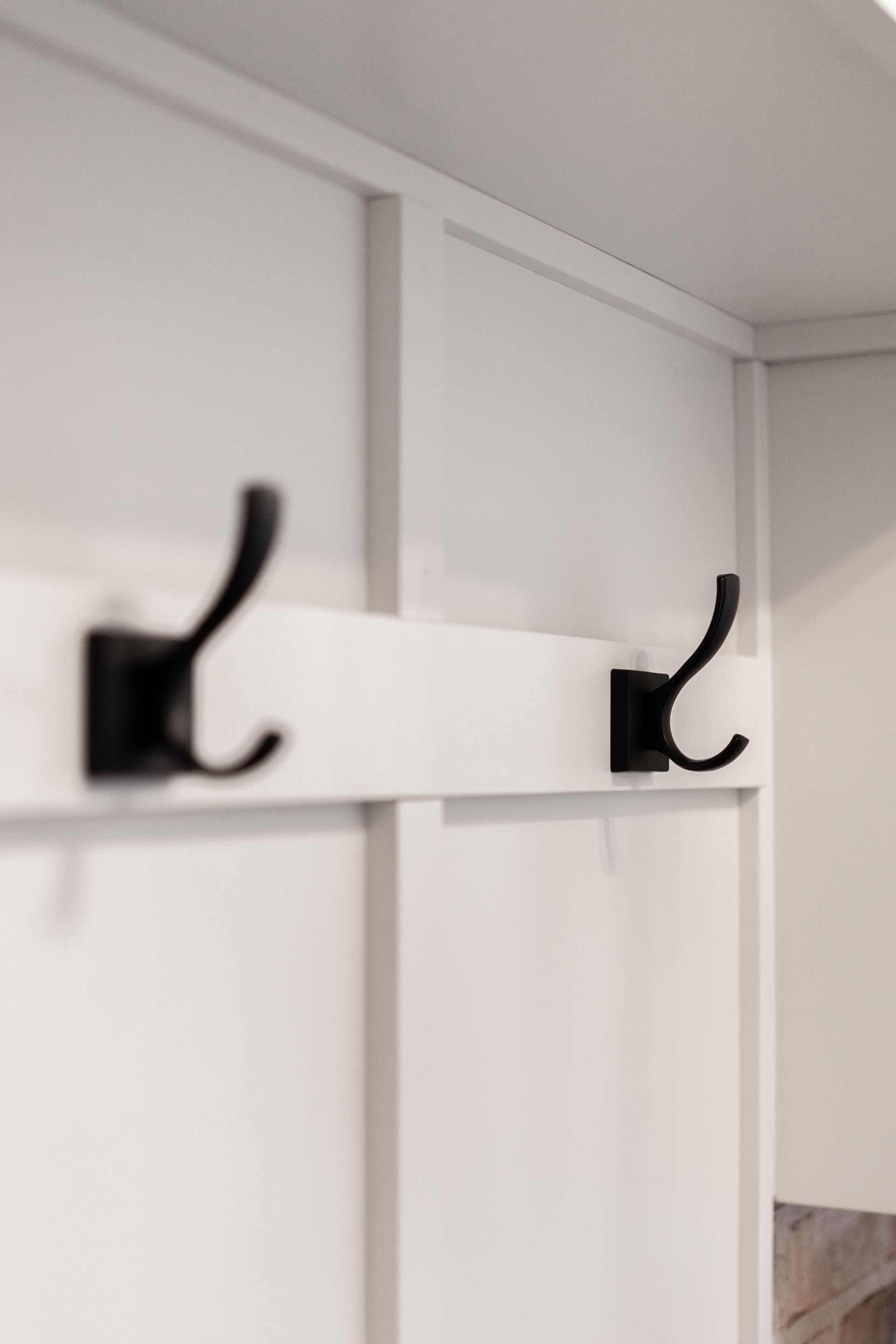 White wall with two black coat hooks.