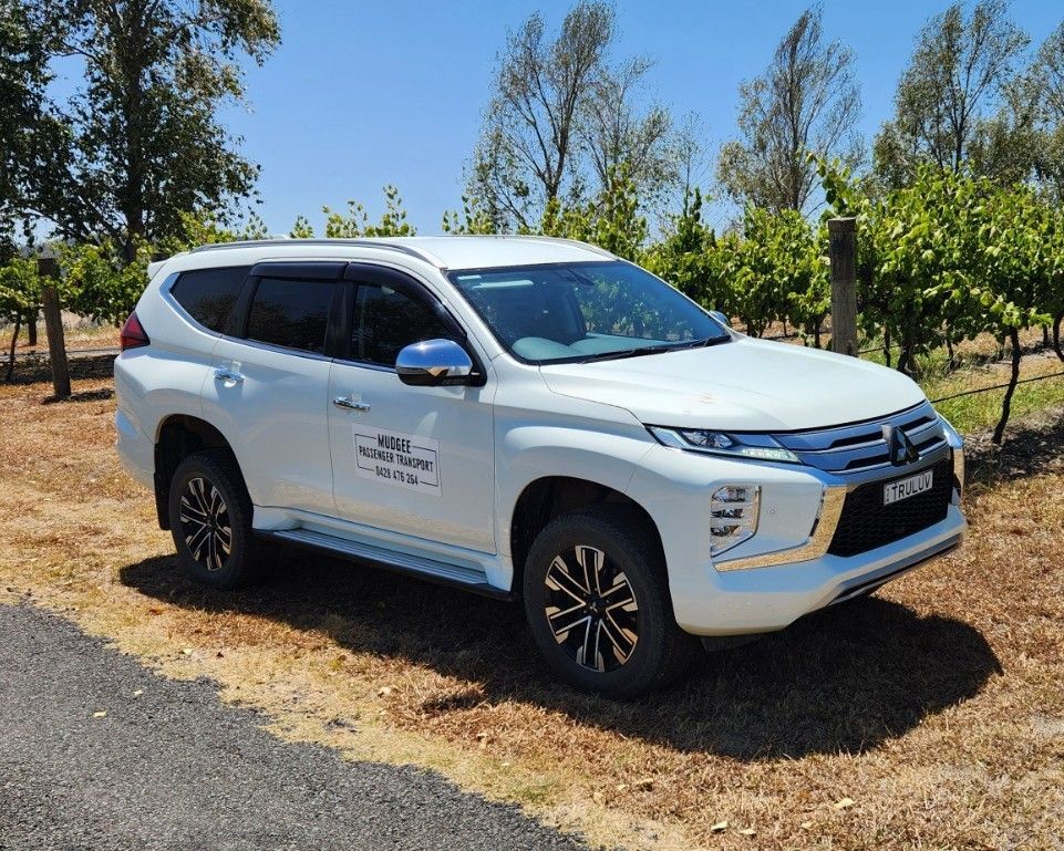 White SUV parked on a roadside beside trees and dry grass under a clear blue sky — Mudgee Passenger Transport in Mudgee, NSW