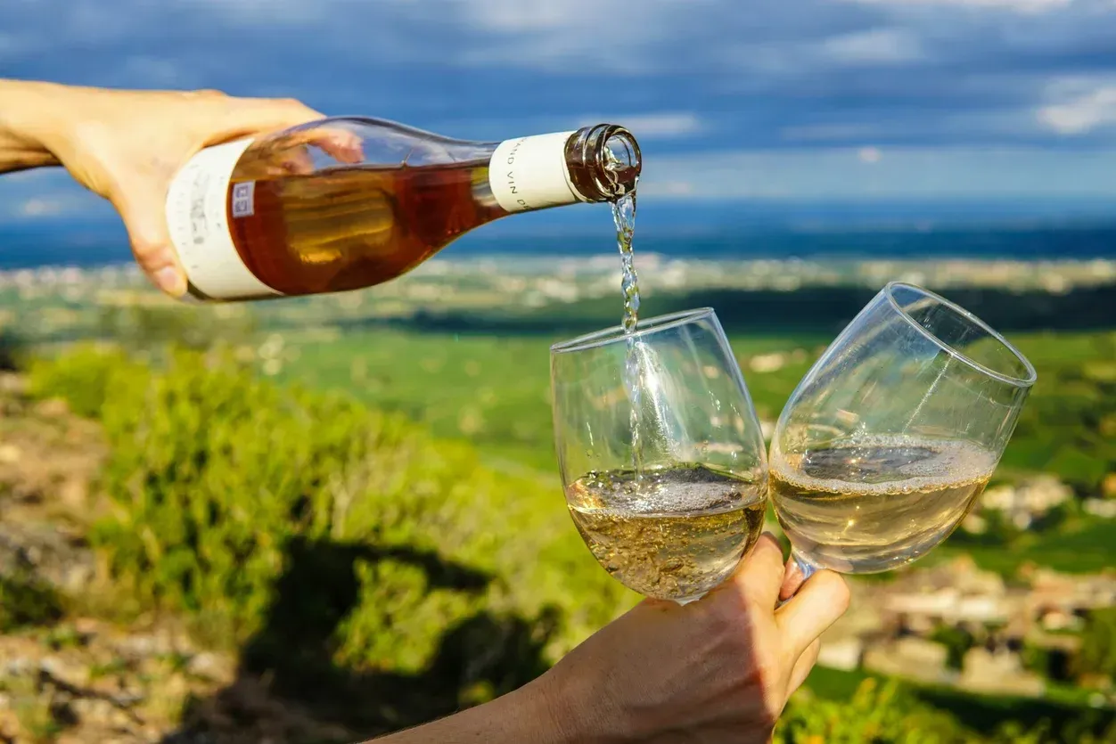A Hand Pours Rosé Wine Into Two Glasses Held Together — Mudgee Passenger Transport in Mudgee, NSW