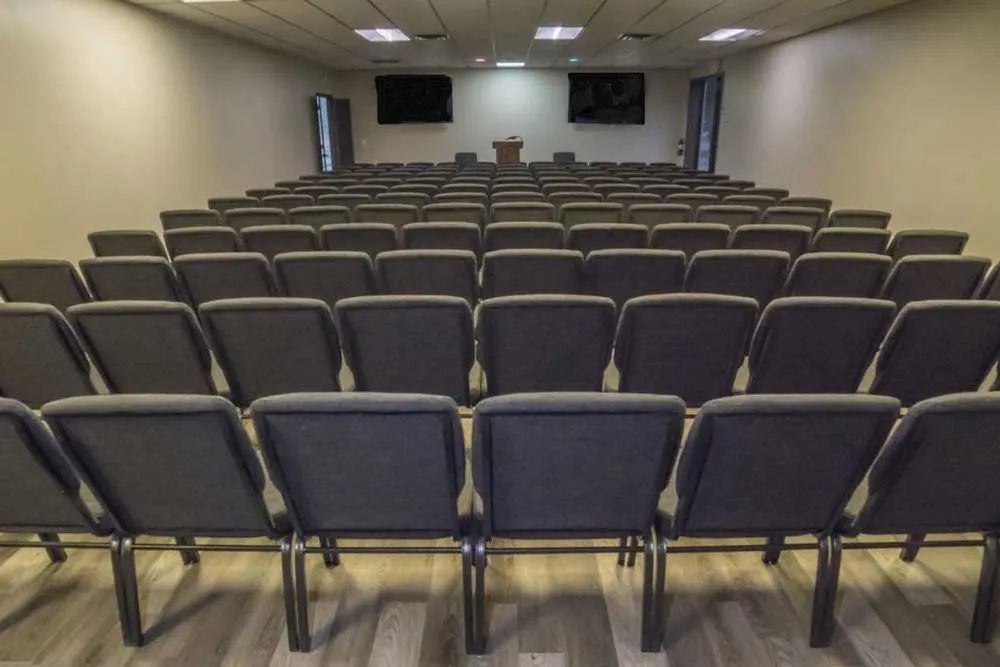 rows of empty chairs in an auditorium with a podium in the middle